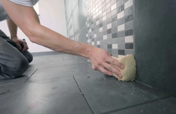 Person reinigt Fliesen mit Schwamm